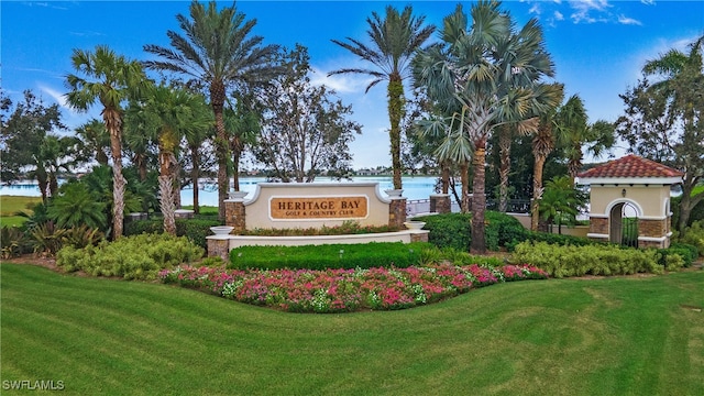 community / neighborhood sign featuring a water view and a yard