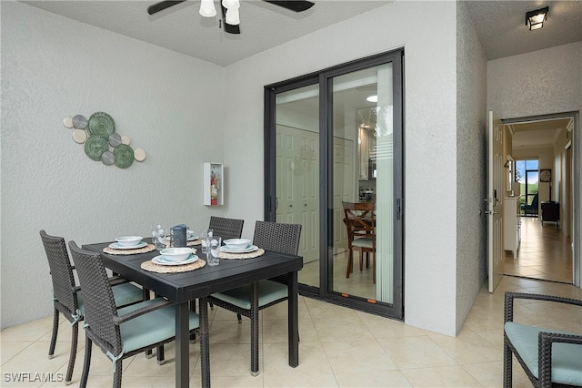 tiled dining area with ceiling fan and a textured ceiling