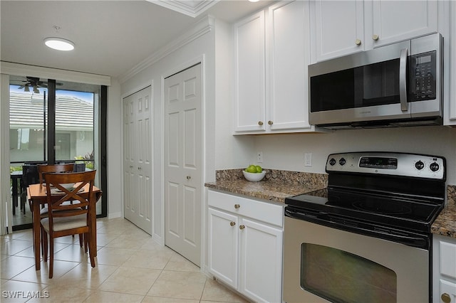 kitchen with white cabinets, appliances with stainless steel finishes, dark stone counters, and ornamental molding