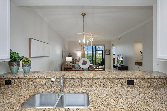 kitchen featuring light stone countertops, sink, hanging light fixtures, a notable chandelier, and ornamental molding