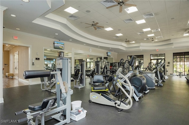 gym featuring a raised ceiling, ceiling fan, and ornamental molding