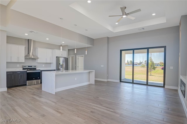 kitchen with white cabinets, pendant lighting, wall chimney range hood, and appliances with stainless steel finishes