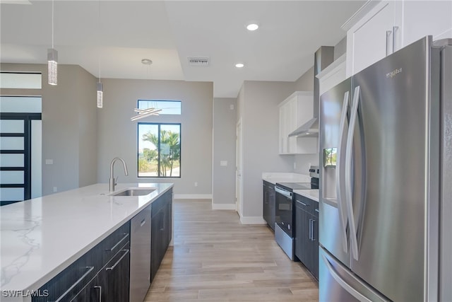 kitchen with light stone counters, stainless steel appliances, sink, pendant lighting, and white cabinetry