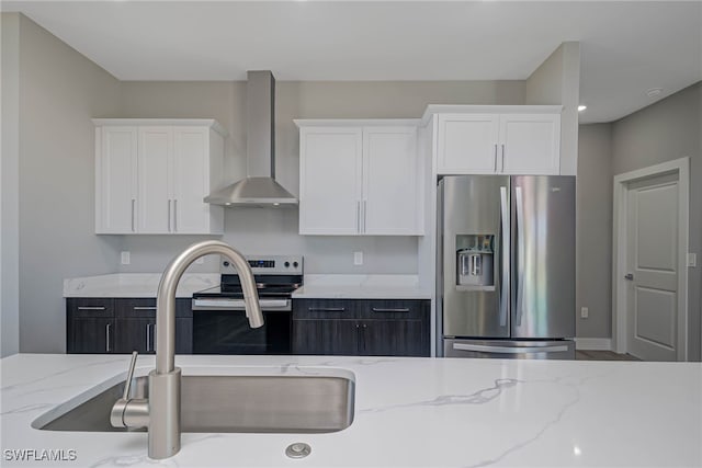 kitchen with stainless steel appliances, white cabinetry, and wall chimney exhaust hood