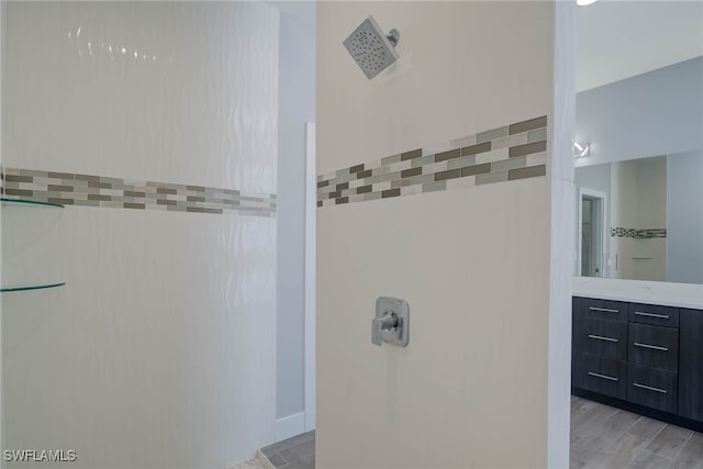 bathroom with walk in shower, wood-type flooring, vanity, and tile walls