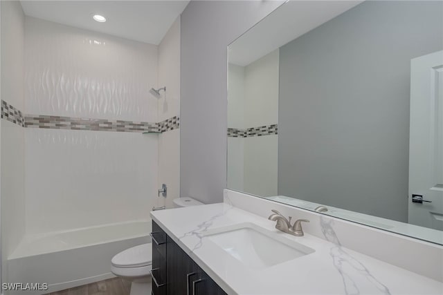 full bathroom with hardwood / wood-style floors, vanity, tiled shower / bath combo, and toilet