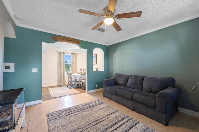 tiled living room featuring a textured ceiling, ornamental molding, and ceiling fan