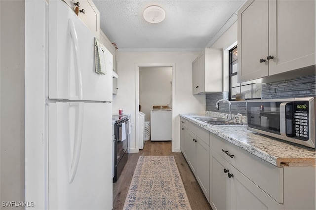 kitchen featuring washer / dryer, sink, white cabinetry, white fridge, and black range with electric cooktop