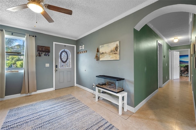 foyer entrance with ceiling fan, a textured ceiling, and ornamental molding