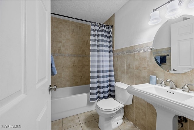 full bathroom featuring a textured ceiling, tile walls, shower / bath combo with shower curtain, and toilet