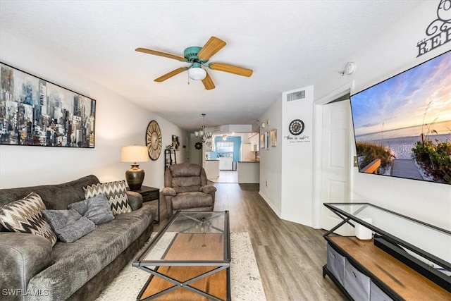 living room featuring ceiling fan with notable chandelier and hardwood / wood-style floors