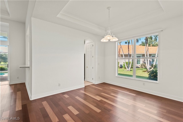 unfurnished dining area with an inviting chandelier, a tray ceiling, crown molding, and dark hardwood / wood-style flooring