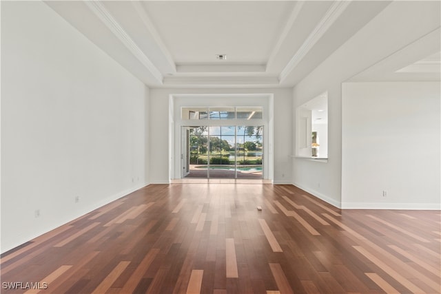 interior space with wood-type flooring, ornamental molding, and a tray ceiling