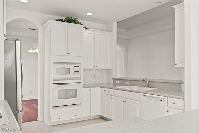 kitchen featuring white appliances, light hardwood / wood-style floors, sink, and white cabinetry