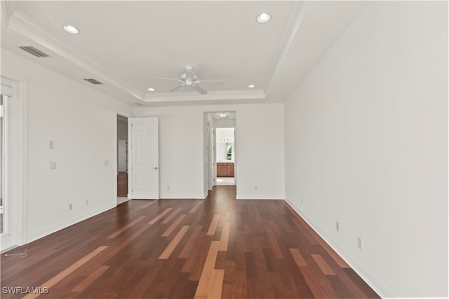 unfurnished room with ceiling fan, a tray ceiling, dark hardwood / wood-style floors, and crown molding