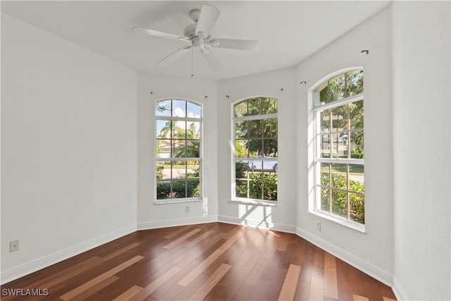 unfurnished room featuring ceiling fan, a wealth of natural light, and dark hardwood / wood-style floors