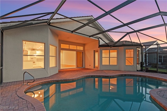 pool at dusk with a patio area and a lanai