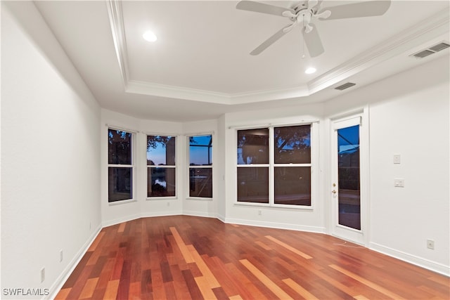 empty room featuring wood-type flooring, a raised ceiling, crown molding, and ceiling fan