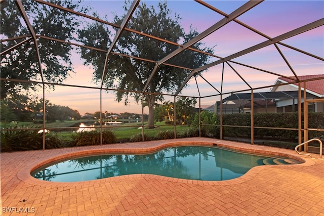 pool at dusk featuring glass enclosure and a patio