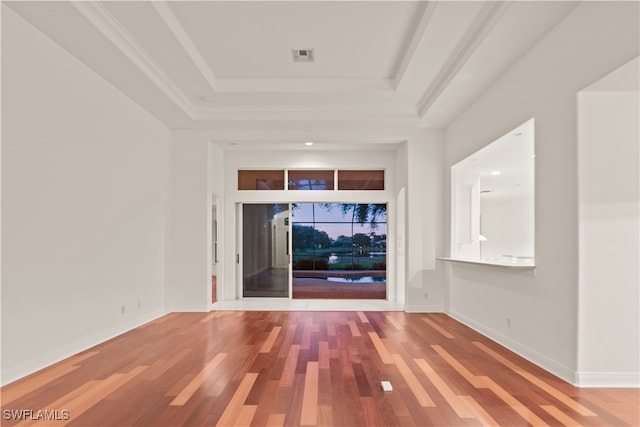 unfurnished room featuring a raised ceiling, ornamental molding, and hardwood / wood-style floors