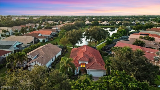 aerial view at dusk featuring a water view