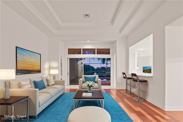 living room with ornamental molding, a tray ceiling, and hardwood / wood-style floors