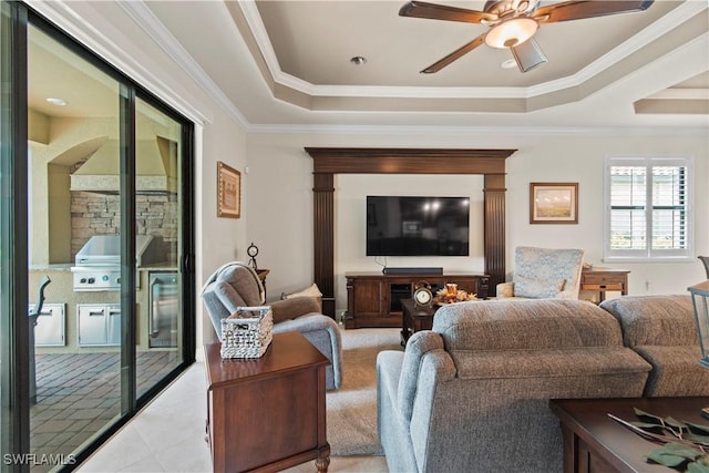 living room with a raised ceiling, crown molding, light tile patterned floors, and ceiling fan