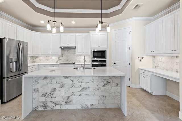 kitchen with a raised ceiling, appliances with stainless steel finishes, sink, and hanging light fixtures