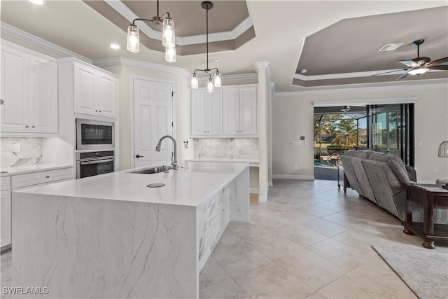 kitchen with sink, white cabinetry, stainless steel oven, decorative light fixtures, and a tray ceiling