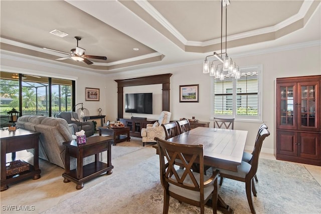 tiled dining space with ornamental molding, ceiling fan with notable chandelier, and a tray ceiling