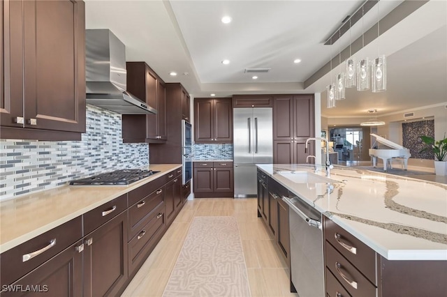 kitchen featuring wall chimney range hood, sink, light tile patterned floors, tasteful backsplash, and stainless steel appliances