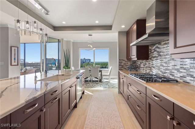 kitchen featuring pendant lighting, wall chimney range hood, sink, light tile patterned floors, and stainless steel appliances