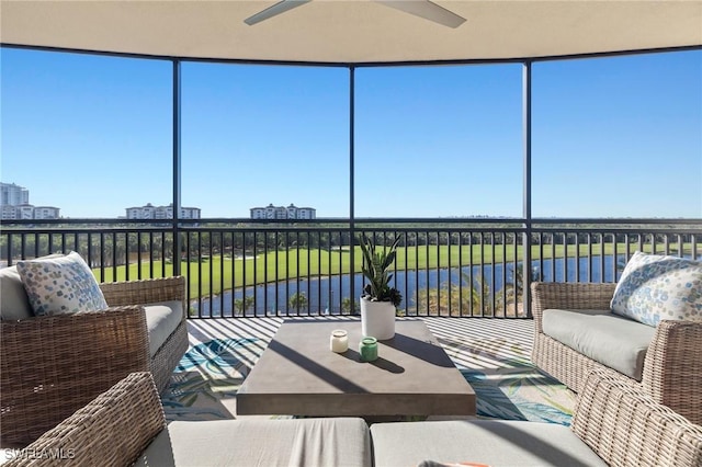 sunroom / solarium featuring ceiling fan and a water view