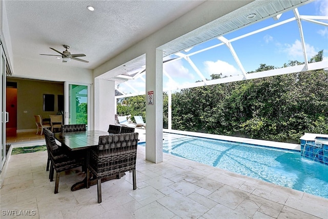 view of pool with ceiling fan, glass enclosure, a patio, and pool water feature