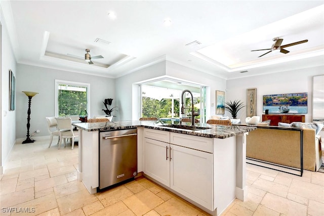 kitchen with dark stone counters, a kitchen island with sink, sink, white cabinets, and a raised ceiling