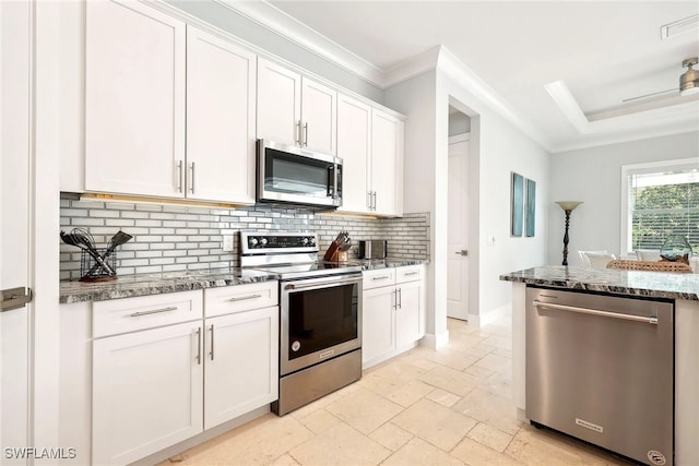 kitchen with dark stone counters, stainless steel appliances, white cabinets, and crown molding