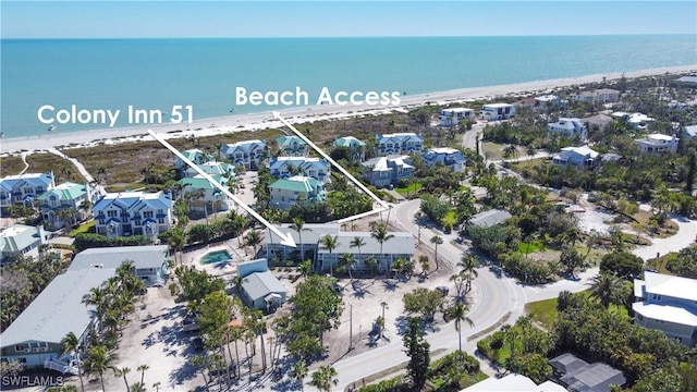 drone / aerial view featuring a view of the beach, a water view, and a residential view