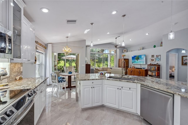 kitchen featuring lofted ceiling, white cabinetry, sink, and decorative light fixtures