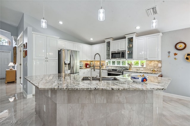 kitchen featuring pendant lighting, white cabinets, appliances with stainless steel finishes, and a large island with sink