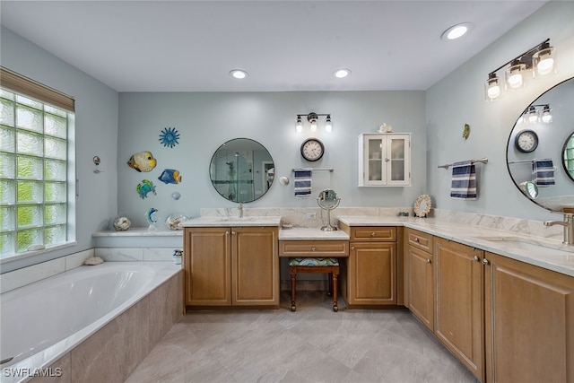 bathroom with a wealth of natural light, tiled tub, and vanity