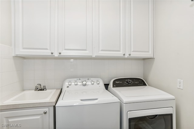 laundry area featuring washing machine and dryer, sink, and cabinets