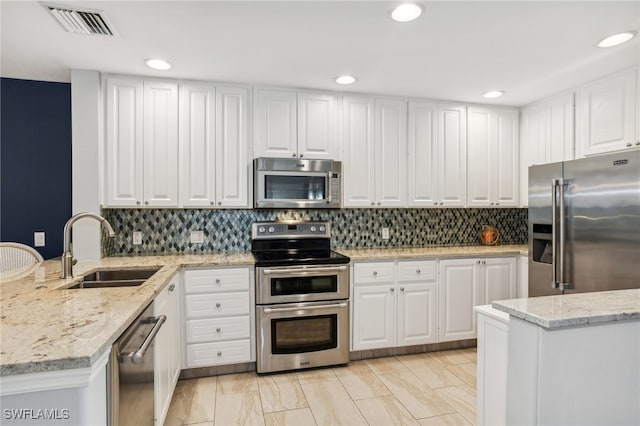 kitchen with light stone counters, appliances with stainless steel finishes, sink, and white cabinetry