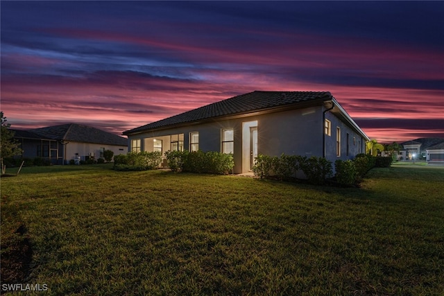 property exterior at dusk featuring a yard