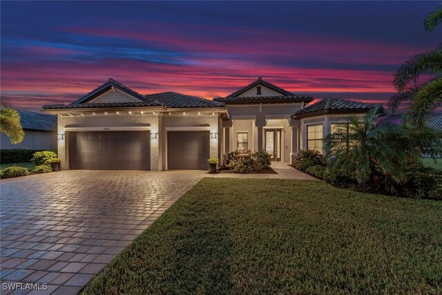 mediterranean / spanish-style home featuring a garage and a lawn