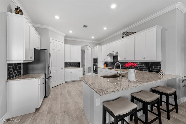 kitchen with tasteful backsplash, sink, light wood-type flooring, white cabinetry, and ornamental molding