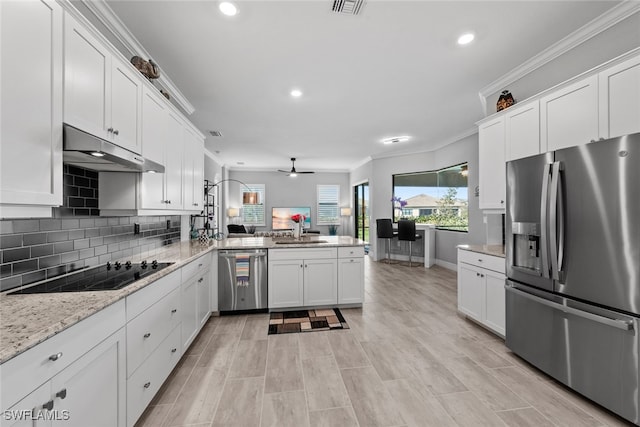 kitchen featuring kitchen peninsula, white cabinets, ornamental molding, sink, and stainless steel appliances