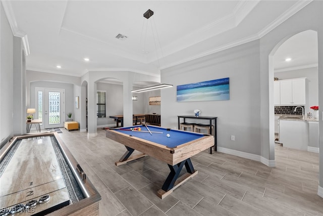 game room featuring crown molding, a tray ceiling, sink, and light wood-type flooring