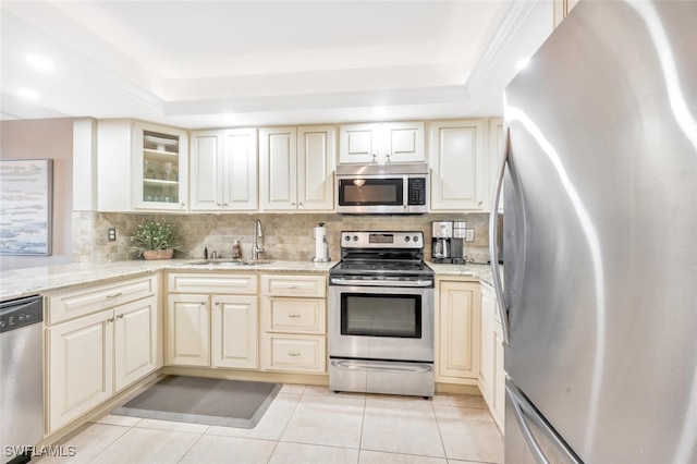 kitchen featuring a tray ceiling, tasteful backsplash, sink, stainless steel appliances, and light tile patterned floors