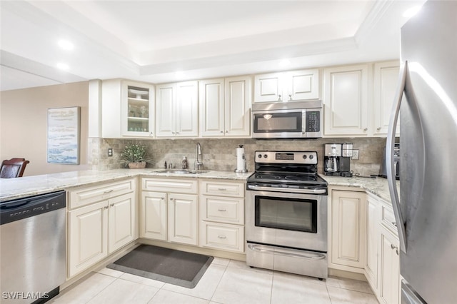 kitchen featuring light stone countertops, stainless steel appliances, a raised ceiling, and sink