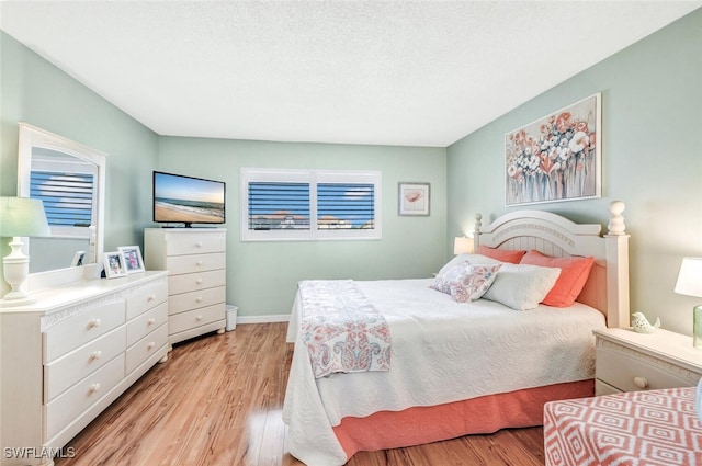 bedroom with a textured ceiling and light hardwood / wood-style floors